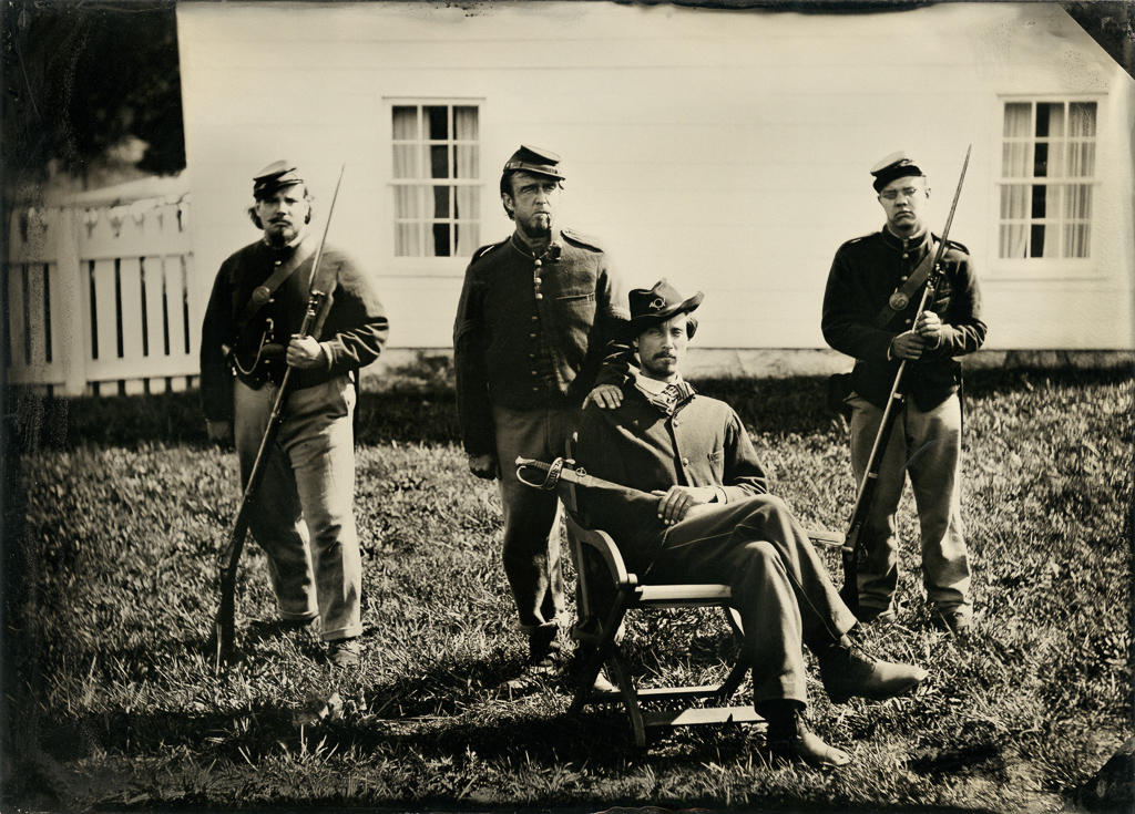 A CIvil War reenactor portraying a Union captain with his sergeant and two privates pose in front of the headquarters of Union General Meade at Gettysburg Military Park in Pennsylvania. Wet plate photograph.