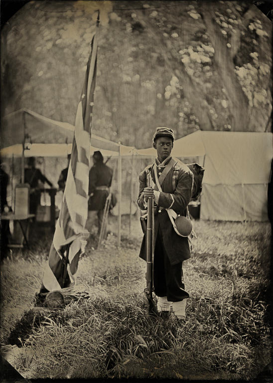 A young African-American man portraying a Union soldier stands guard at a Civil War reenactment in Acton, California. In 1863 African-Americans were allowed to form their own segregated regiments commanded by white officers. Wet plate photograph

