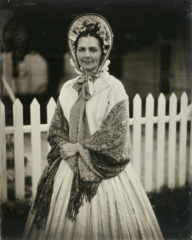 Wearing an outfit she made herself, Civil War reenactor Maegen Hensley poses in front of the Drum Barracks Civil War Museum in Los Angeles, California. Hensley is a member of the Historical Citizens Association, a nonprofit Southern California reenacting group that seeks to educate the public about American history. Wet-plate photograph. 
